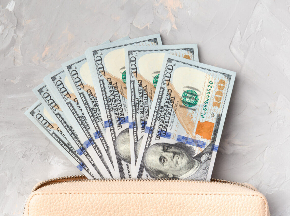 Stylish wallet with dollars banknotes on a light gray background, top view.